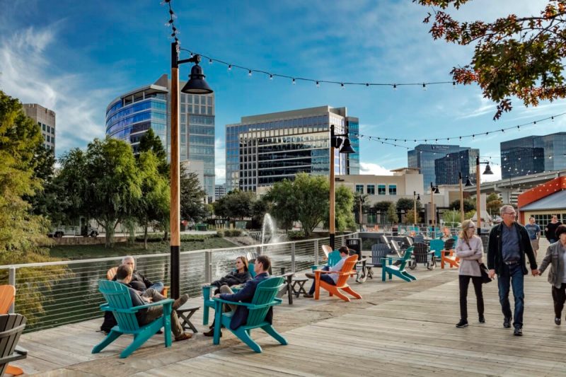 people sit and saunter along plano's waterfront boardwalk.